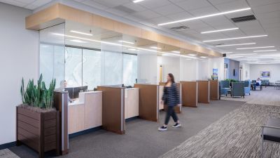 Healthcare clinic reception area with private check-in stations, glass partitions, comfortable waiting seating, and a spacious lobby designed to enhance patient privacy and comfort.