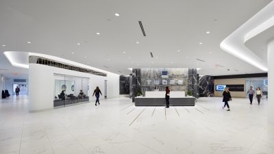 Completed lobby at Two22 featuring a marble reception desk, curved architectural details, and people moving through the renovated space.