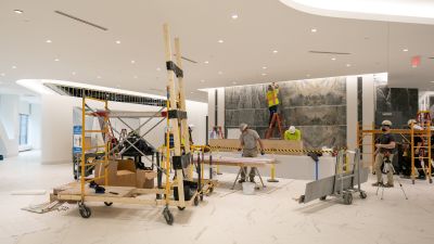 Construction team installing a large stone feature wall in the lobby of the Two22 office tower during renovation.