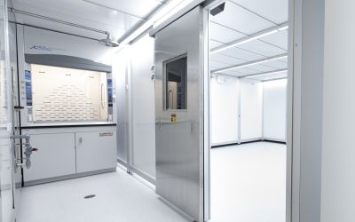 Advanced laboratory with a chemical fume hood, cleanroom entry door, and bright controlled environment designed to support scientific research, testing, and precision manufacturing.