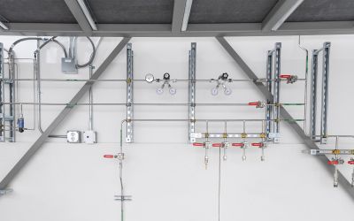 Valves, gagues, and thin piping adhered to the wall in a science and tech setting.