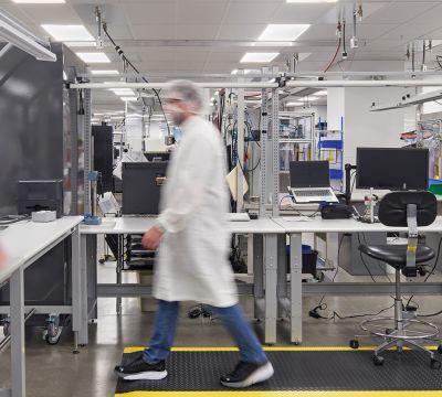 A person in a white lab coat walks through a clean, modern laboratory workspace that Gardner built.