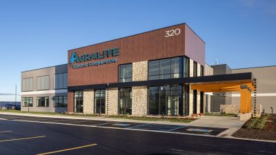 Front facade of the Agralite Electric Cooperative building showing the illuminated "AGRALITE" sign, stone and wood paneling, and glass entrance.