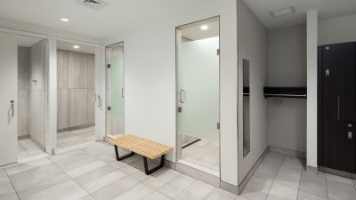Modern locker room with private changing areas, showers, lockers, and bench seating.