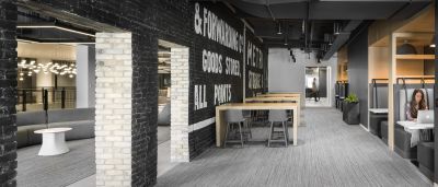 An industrial-style office with exposed brick walls, booth seating, and painted text on a black wall.