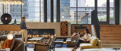 Cozy lounge with a gas fireplace, leather armchairs, and floor-to-ceiling windows overlooking the city skyline.