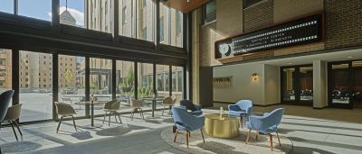 Double-height lobby with blue armchairs around a brass table beneath a vintage-style split-flap sign reading "Northstar Center."