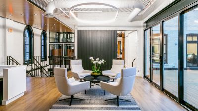 A bright meeting area with four white armchairs around a black table under a circular ceiling light.